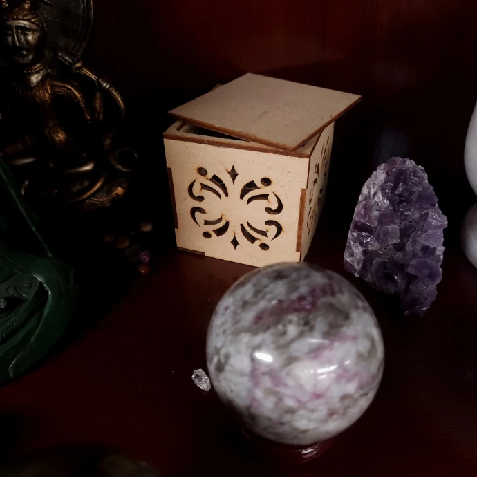 A carved wooden box with the lid ajar keeps secrets on the back of a shelf full of crystals